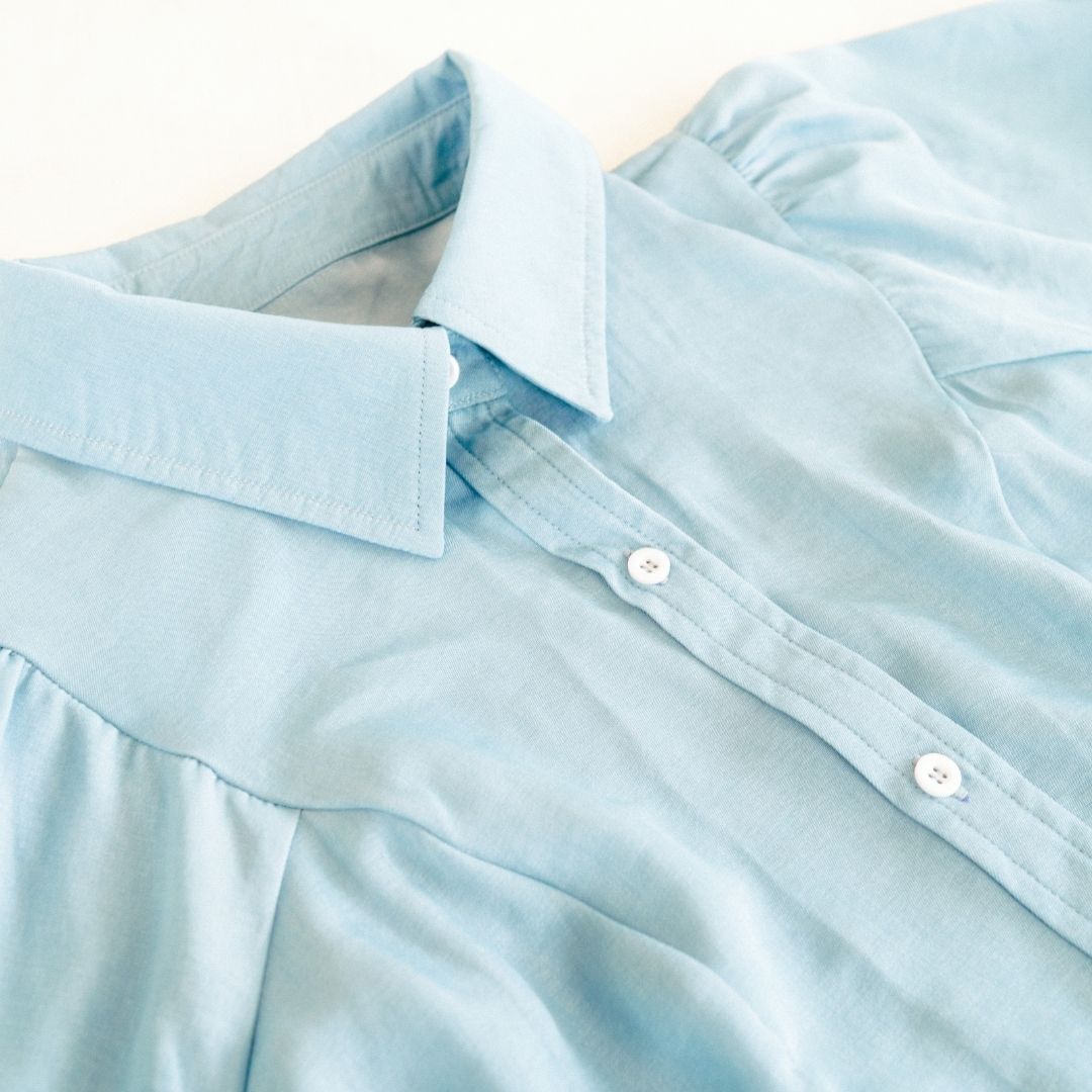 Light blue shirt with white collar and buttons on a white background