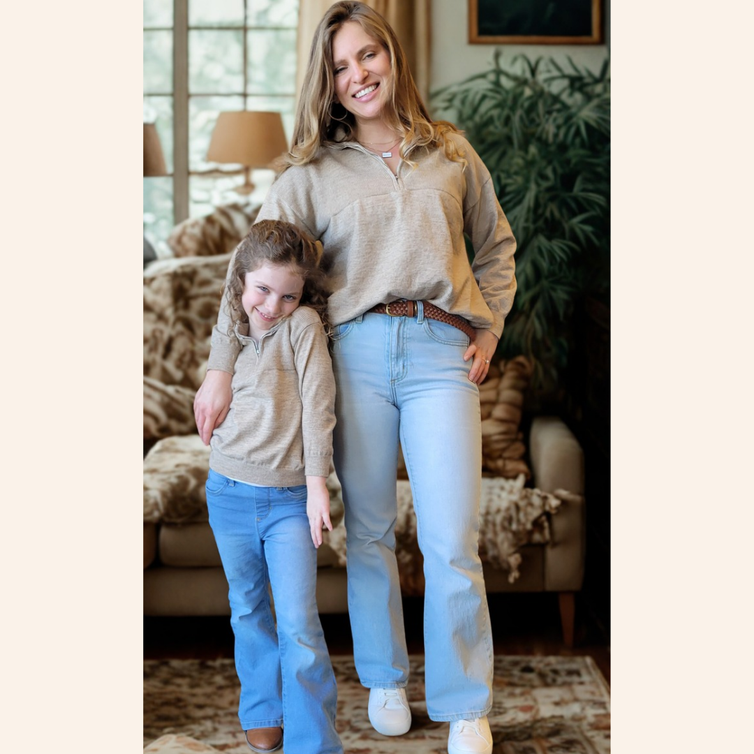 Woman and child standing together in a living room wearing matching outfits.
