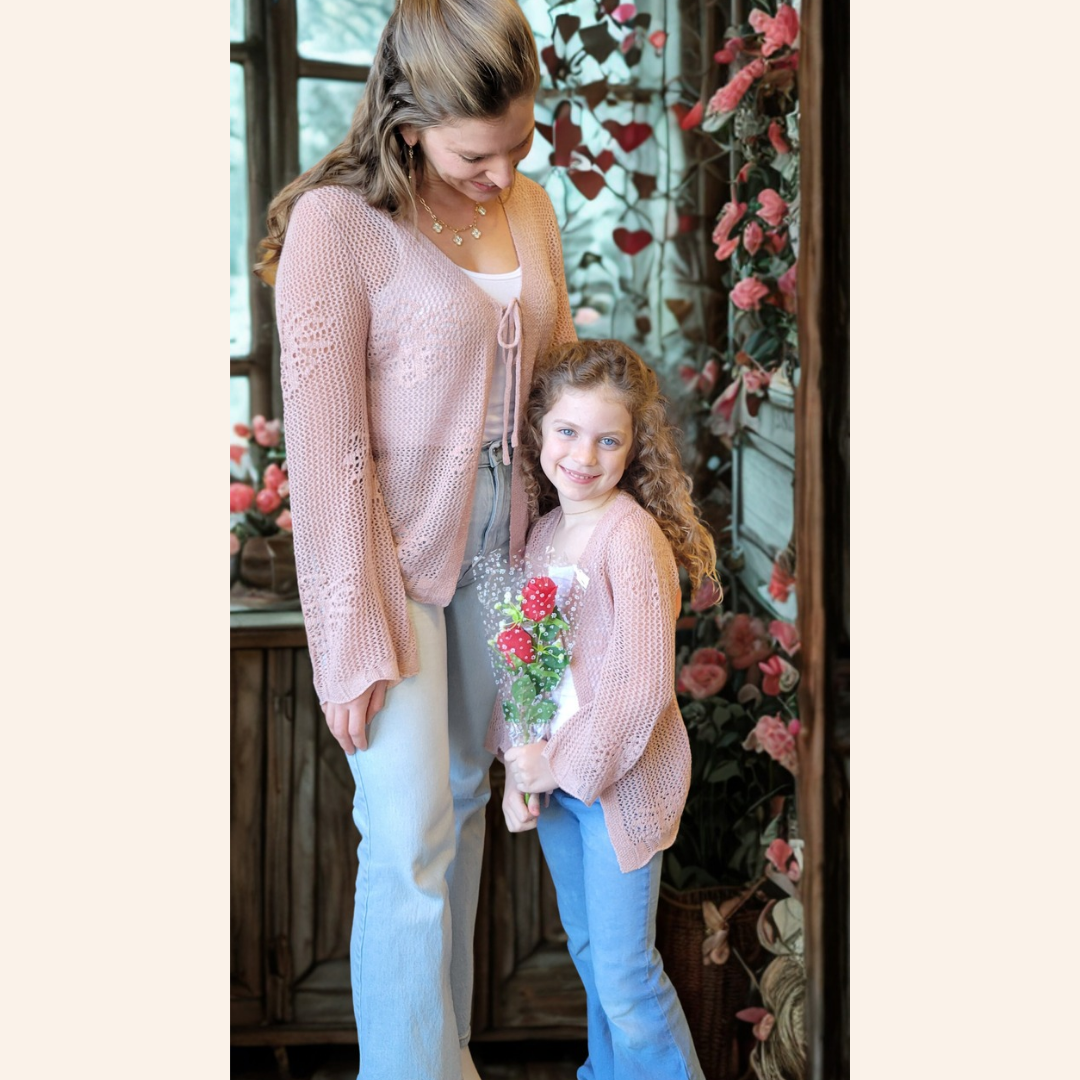 Two women standing together with one holding flowers, surrounded by decorative elements.