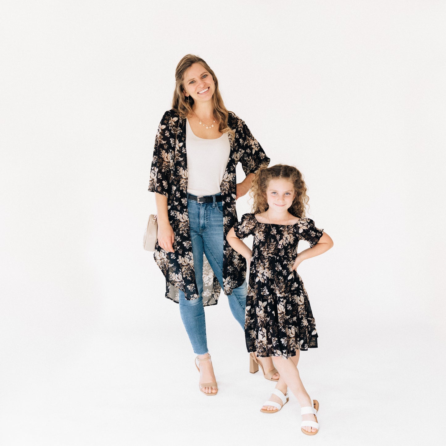 Woman and young girl wearing matching floral outfits on a white background