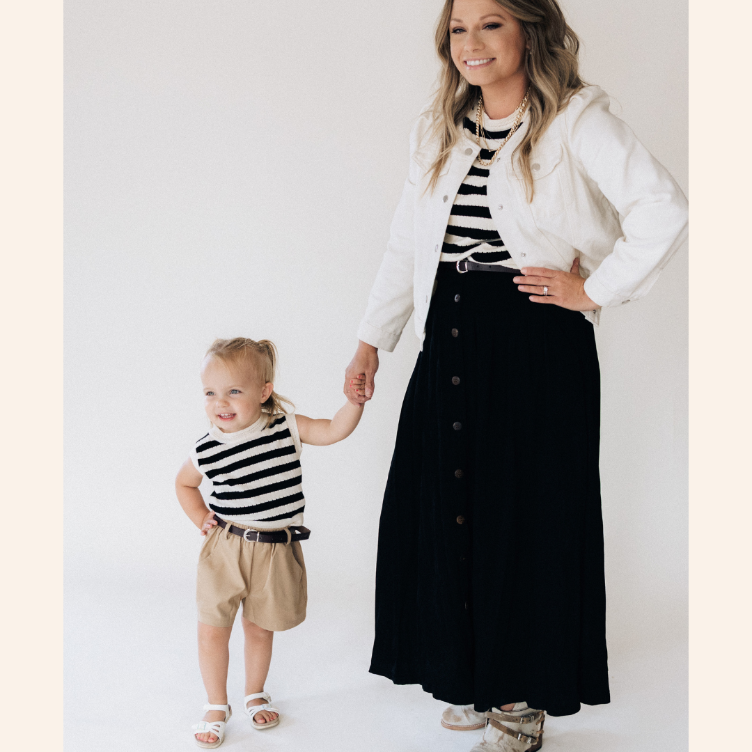 Woman and child wearing matching black and white striped outfits with a white background