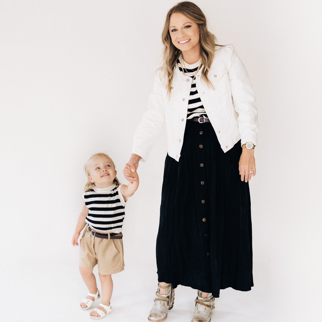 Woman and child wearing matching black and white striped outfits with a white background