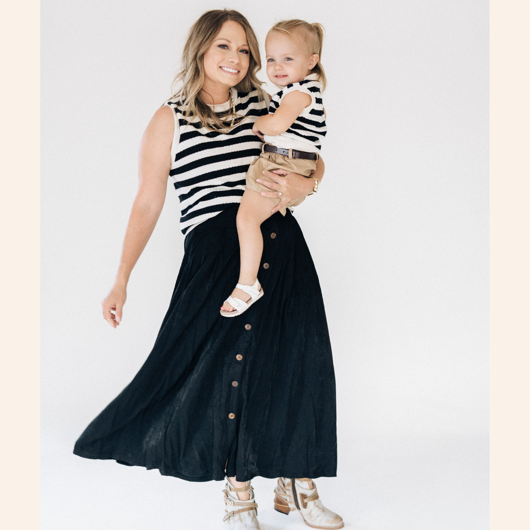 Woman holding a child both wearing matching striped outfits against a white background